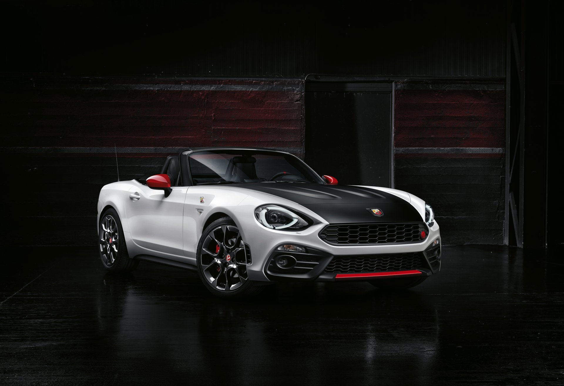 A striking white Fiat 124 Spider showcases its sleek design against a dark backdrop, highlighting its sporty features and modern charm in a 4K Ultra HD resolution.