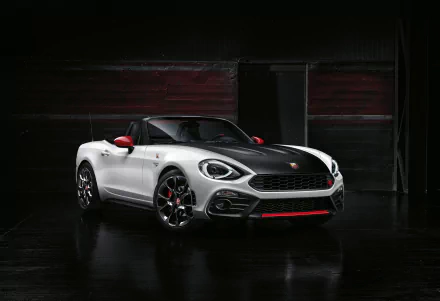 A striking white Fiat 124 Spider showcases its sleek design against a dark backdrop, highlighting its sporty features and modern charm in a 4K Ultra HD resolution.