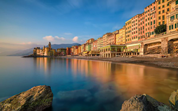 Colorful houses line the coastline of the picturesque Italian town of Portofino, reflecting in calm waters under a clear sky in this vibrant HD desktop wallpaper.