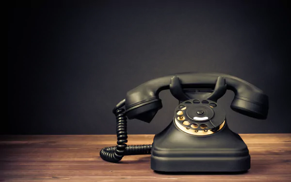 Close-up of a vintage man-made rotary telephone on a wooden surface, captured in 4K Ultra HD for a PC desktop wallpaper and background.