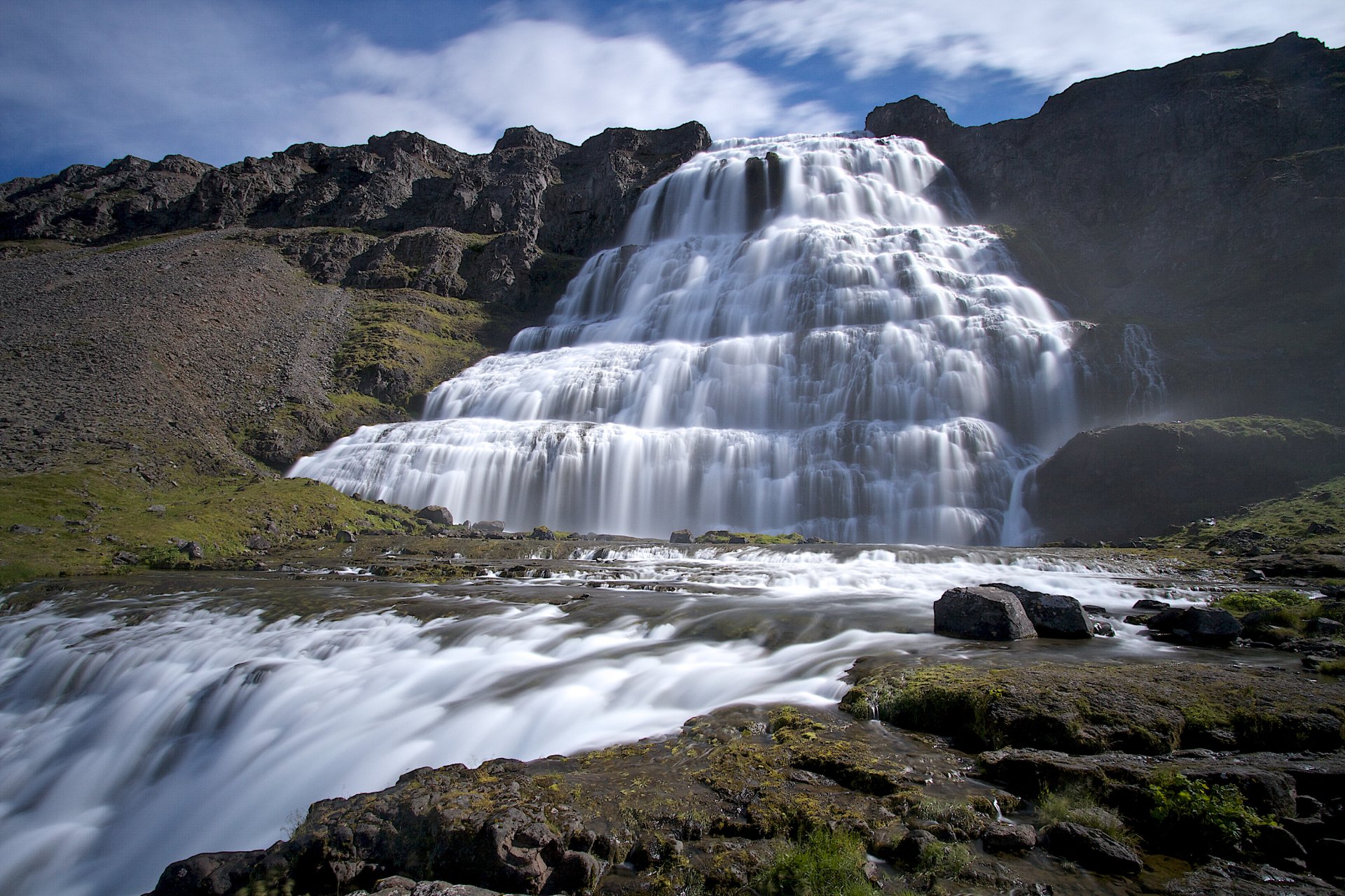HD desktop wallpaper capturing the majestic Dynjandi waterfall cascading over rugged cliffs in Iceland’s natural landscape under a bright blue sky.