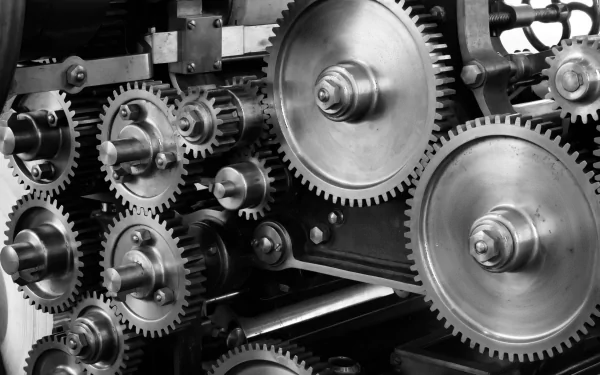 Black and white close-up of interconnected man-made gears, showcasing intricate mechanical details in a 4K Ultra HD PC desktop wallpaper and background.