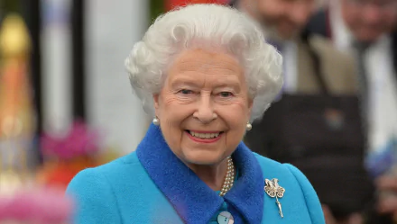 HD desktop wallpaper featuring a smiling Queen Elizabeth II wearing a blue coat and pearl necklace.