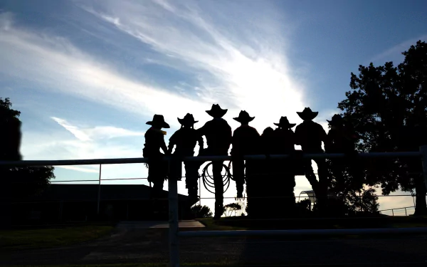 Silhouette of cowboys and a cowgirl at a rodeo captured against a bright sky, creating a striking HD desktop wallpaper background.