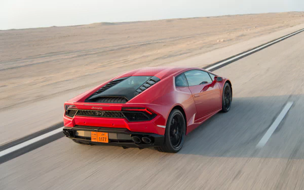 HD desktop wallpaper featuring a red Lamborghini Huracan supercar driving on a desert road, showcasing its sleek design and dynamic performance.