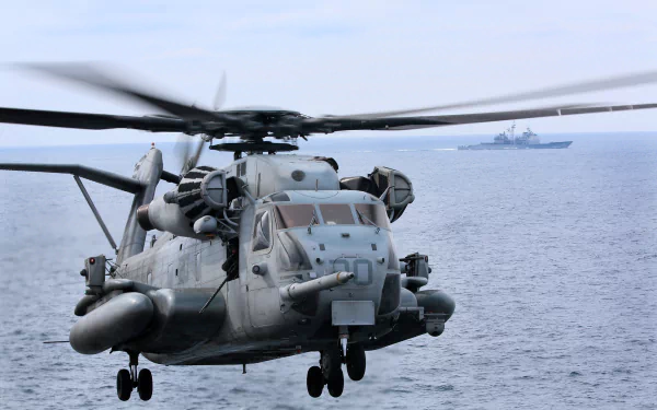 Close-up of a Sikorsky CH-53 Sea Stallion helicopter flying over the ocean, showcasing its military design and powerful rotors against a serene backdrop.