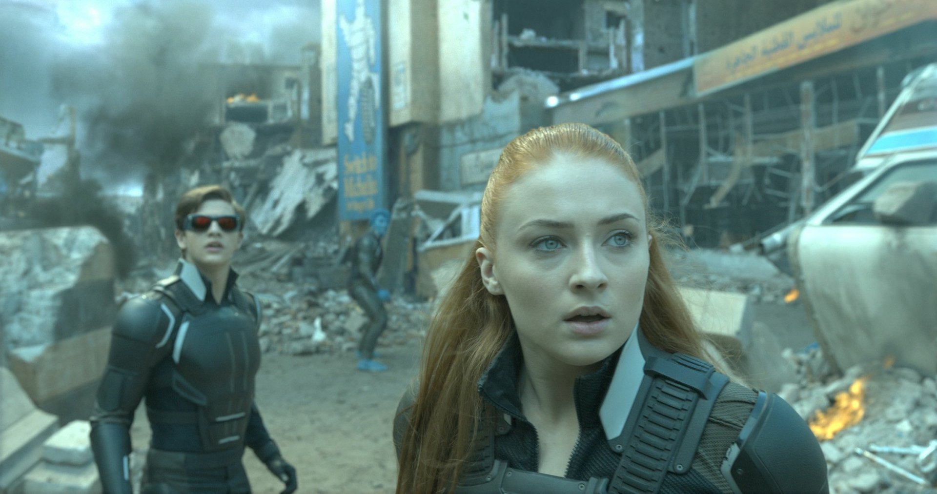 A dramatic scene from X-Men: Apocalypse featuring Cyclops, portrayed by Tye Sheridan, and Jean Grey, played by Sophie Turner, amidst chaos and destruction.