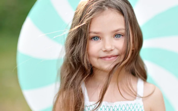 HD desktop wallpaper featuring a little girl with striking blue eyes, captured in a vibrant, professional child photography portrait.