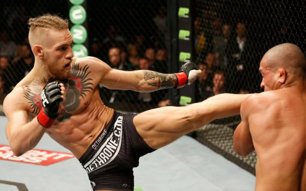 A dynamic UFC action shot featuring Conor McGregor mid-fight, delivering a powerful kick to his opponent, capturing the intensity of sports competition in high definition.