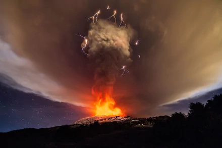 A dramatic HD desktop wallpaper showcasing a volcano erupting with fiery lava and ash, illuminated by flashes of lightning against a swirling, cloud-filled sky.