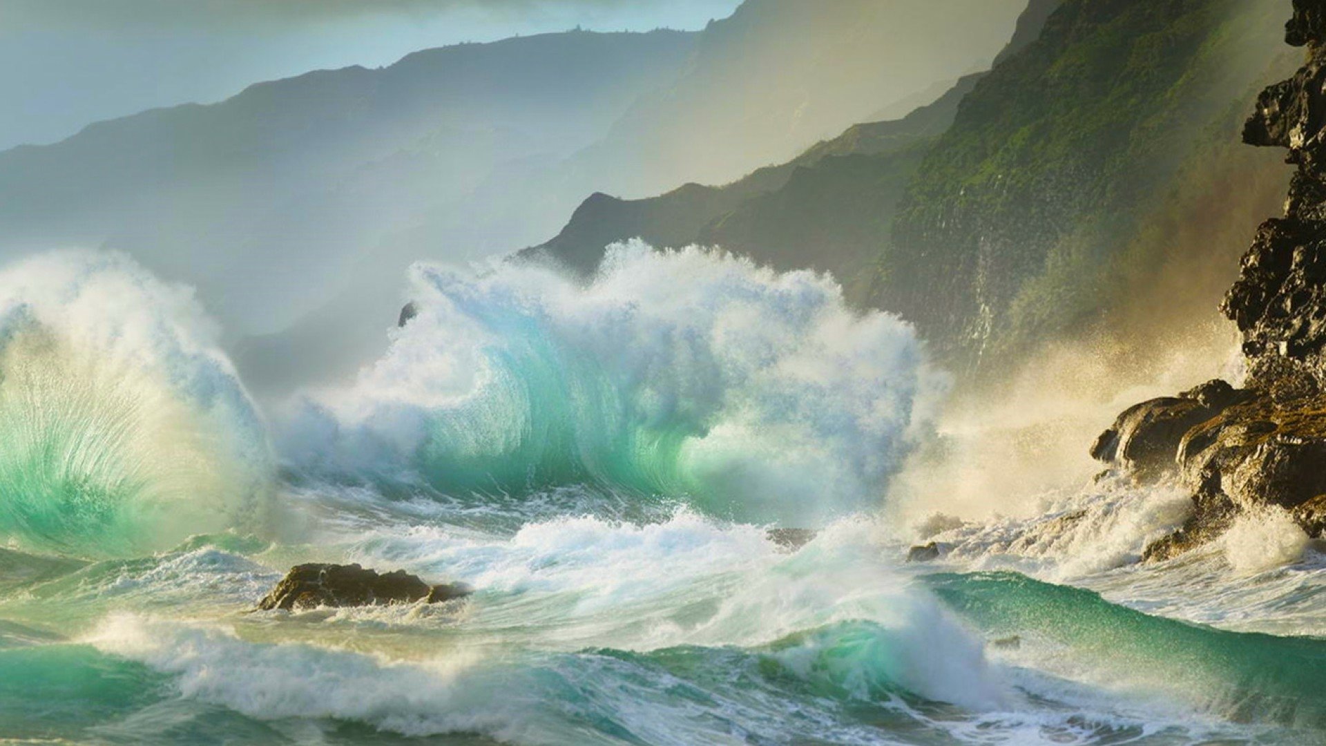 HD desktop wallpaper showcasing powerful ocean waves crashing against rocky cliffs under a misty sky, capturing the raw beauty of sea and nature.