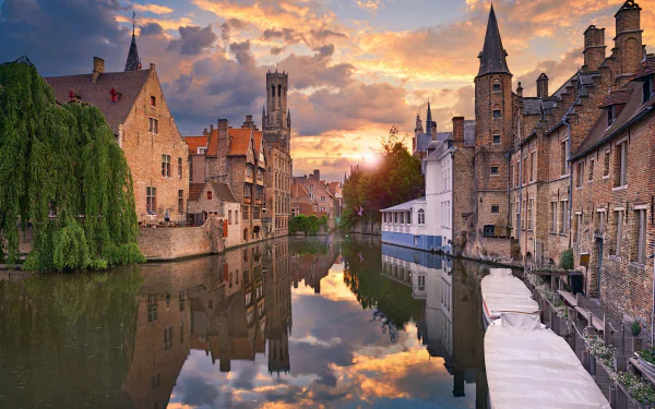 HD desktop wallpaper capturing a serene man-made canal scene in Bruges, with historic buildings and a vibrant sunset reflecting on the water.
