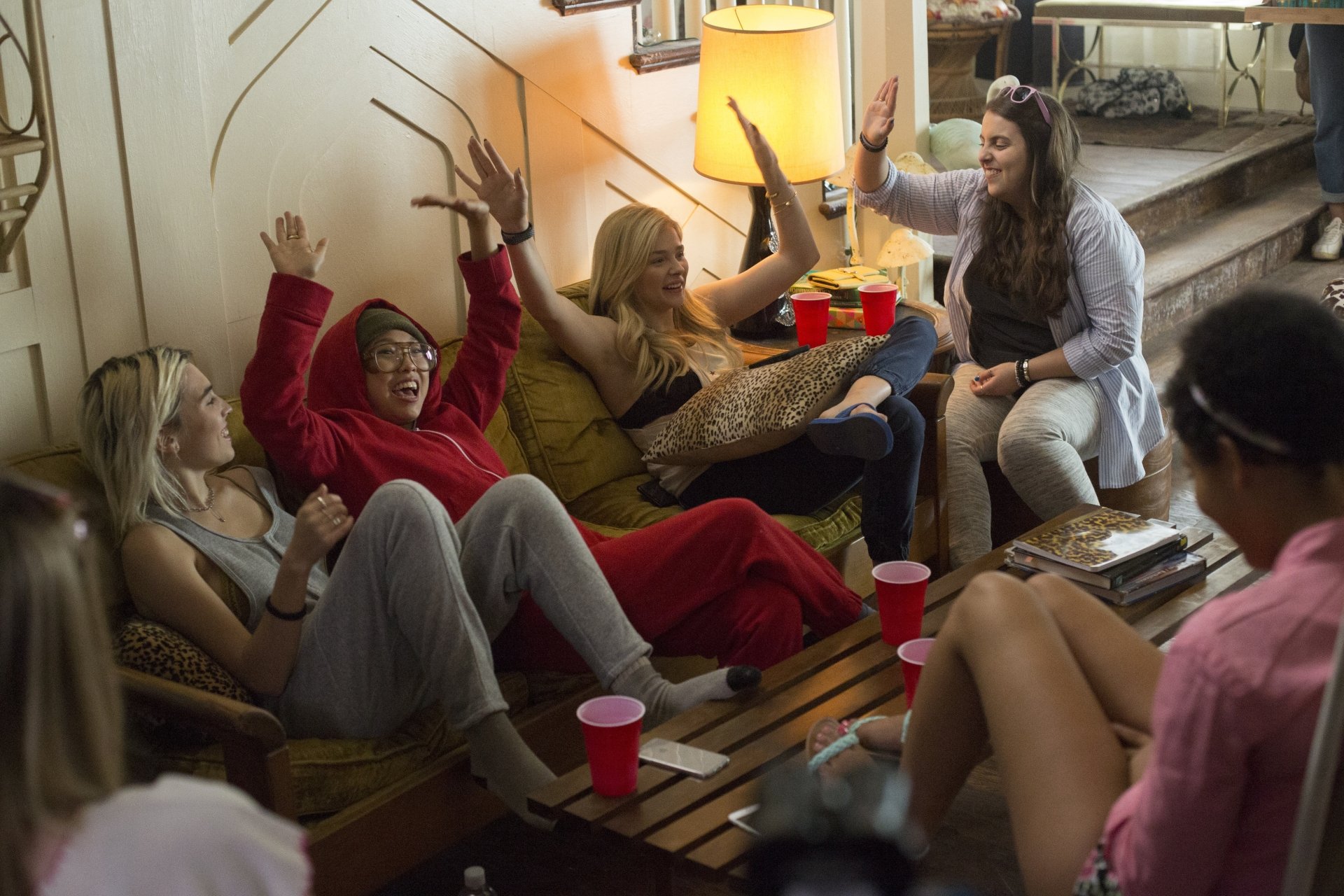 5K Ultra HD PC wallpaper: movie scene (Neighbors 2: Sorority Rising) showing women lounging on couches, holding red cups and high-fiving at a lively sorority party.