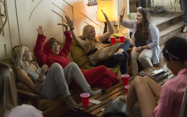 5K Ultra HD PC wallpaper: movie scene (Neighbors 2: Sorority Rising) showing women lounging on couches, holding red cups and high-fiving at a lively sorority party.