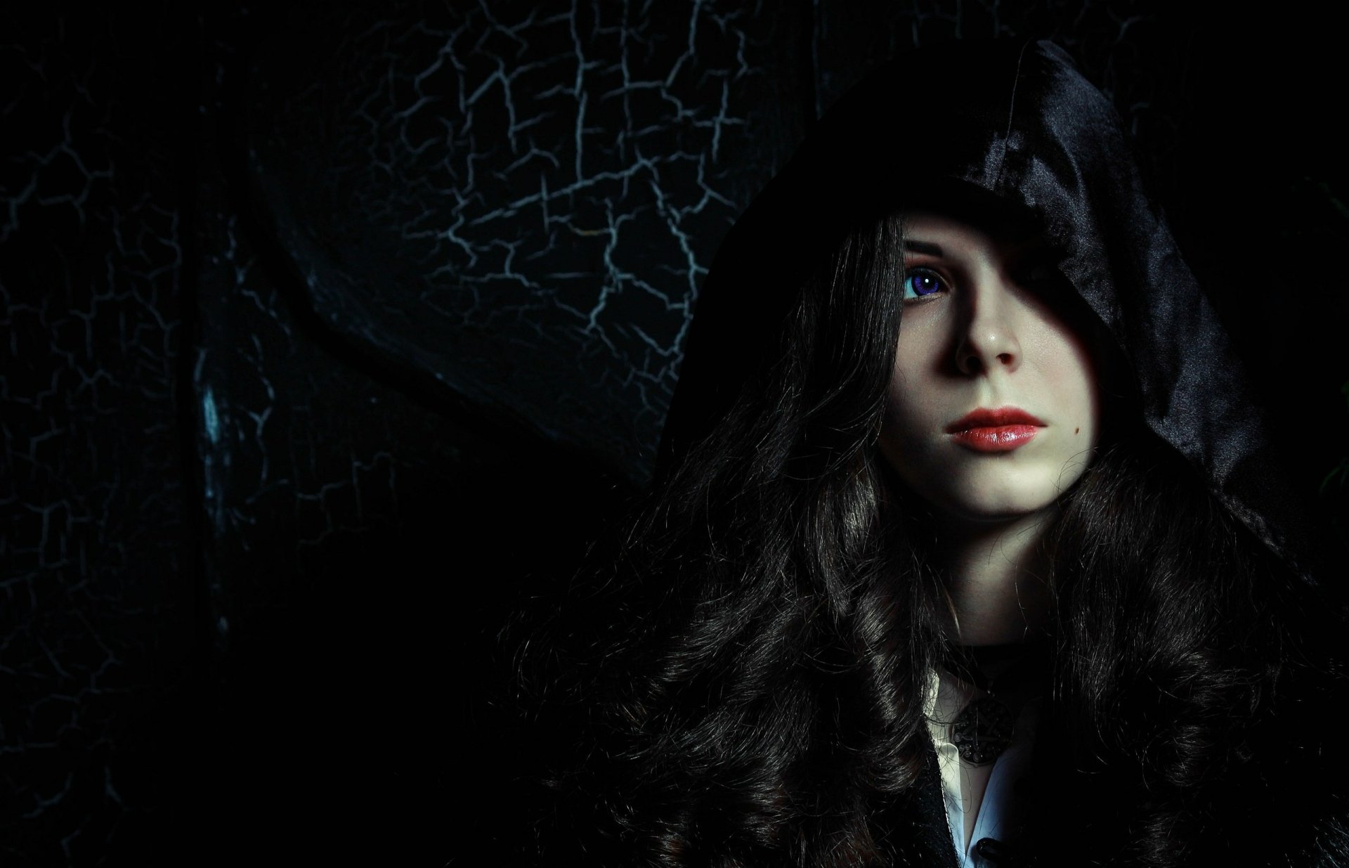 HD PC desktop wallpaper featuring a woman cosplaying Yennefer of Vengerberg from The Witcher 3: Wild Hunt, with a dark hooded cloak and striking blue eyes.