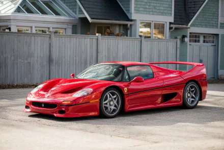 Red Ferrari F50 sports car parked in front of a house, captured in a 4K Ultra HD desktop wallpaper showcasing the iconic vehicle’s sleek design.