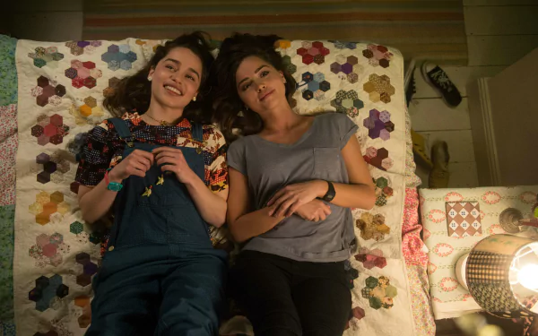 Jenna Coleman and Emilia Clarke lie on a colorful quilt, sharing a relaxed moment in a scene from the movie Me Before You, presented in 4K Ultra HD.
