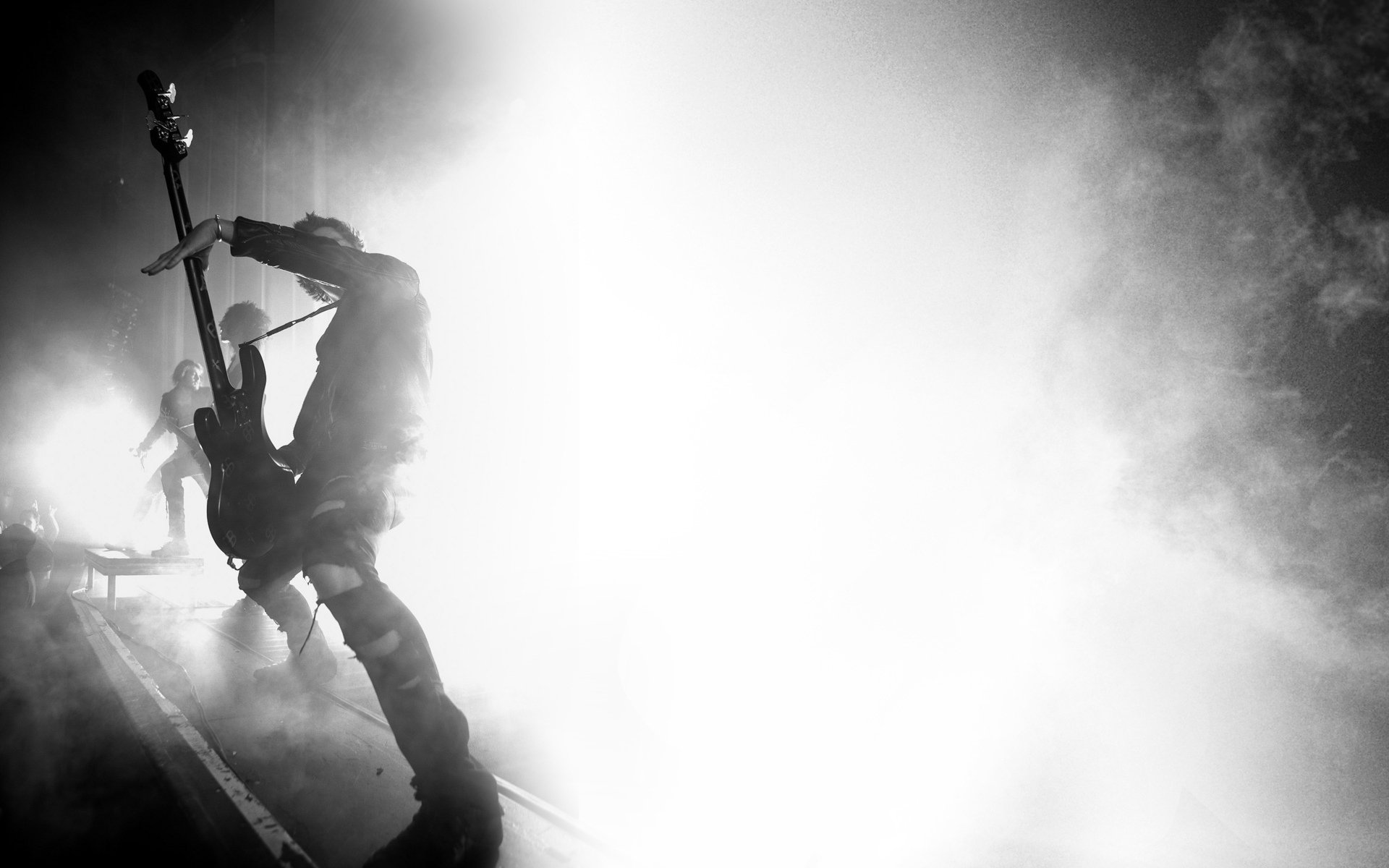 Black and white HD wallpaper featuring a musician playing guitar on stage, capturing the intense energy of a live Asking Alexandria performance.