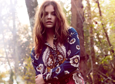Portrait of celebrity model Barbara Palvin in a floral patterned outfit set against a sunlit forest backdrop, featured as an HD PC desktop wallpaper.
