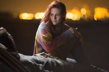 A serene moment from American Ultra, featuring Kristen Stewart with a vibrant sweater, set against a softly lit urban backdrop. This 4K Ultra HD image captures an intimate scene.