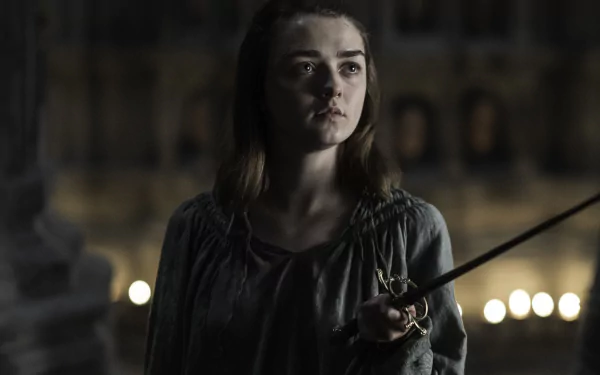 A high-definition wallpaper featuring Maisie Williams as Arya Stark from the TV show Game of Thrones, showcasing a determined expression with a sword in hand.