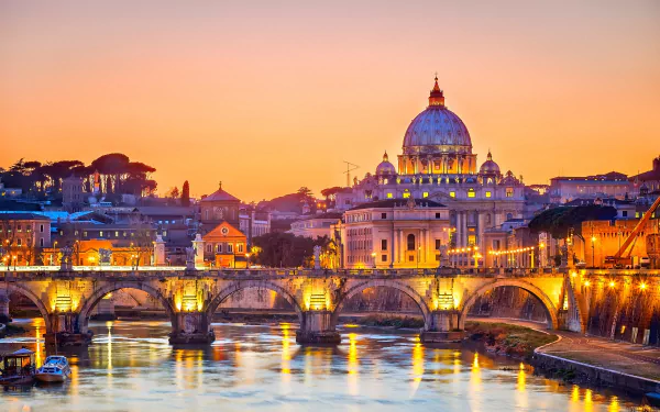 A stunning evening view of Rome, showcasing the illuminated dome and vibrant buildings along the river, with a picturesque bridge enhancing the city's beauty.