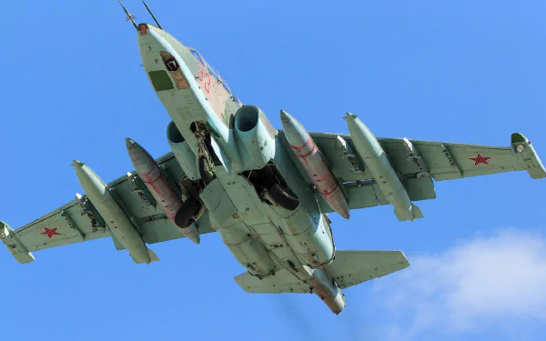 HD desktop wallpaper featuring a military Sukhoi Su-25 jet fighter warplane soaring against a clear blue sky.