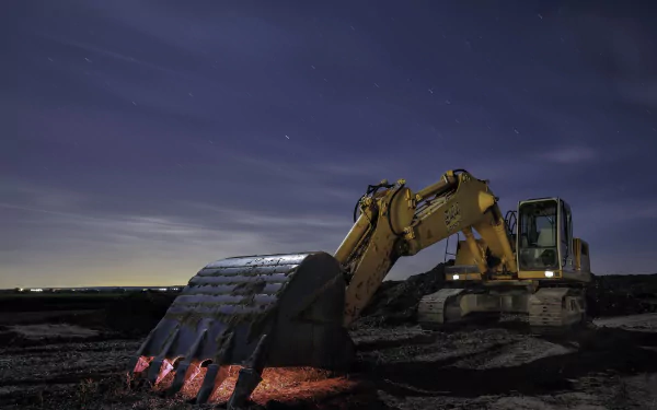 HD PC desktop wallpaper of a yellow excavator at night, its bucket casting a red glow on dark soil beneath a star-filled sky