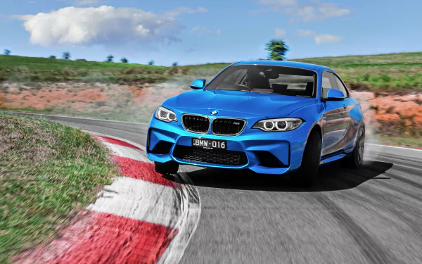 A vibrant blue BMW M2 car speeding on a racetrack with clear skies, captured as an HD PC desktop wallpaper showcasing the vehicle's dynamic design and performance.