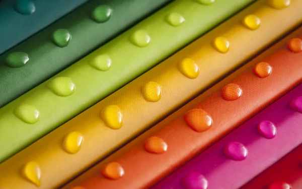 Close-up of vibrant rainbow-colored stripes with water drops, creating a colorful abstract pattern for an HD PC desktop wallpaper background.