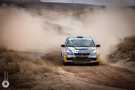 A Mitsubishi Lancer Evolution maneuvers through a dusty landscape, showcasing its rally-inspired design in this high-definition desktop wallpaper.