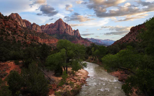 Scenic view of a river winding through lush greenery and rugged mountains in Zion National Park, Utah, captured in an HD desktop wallpaper.