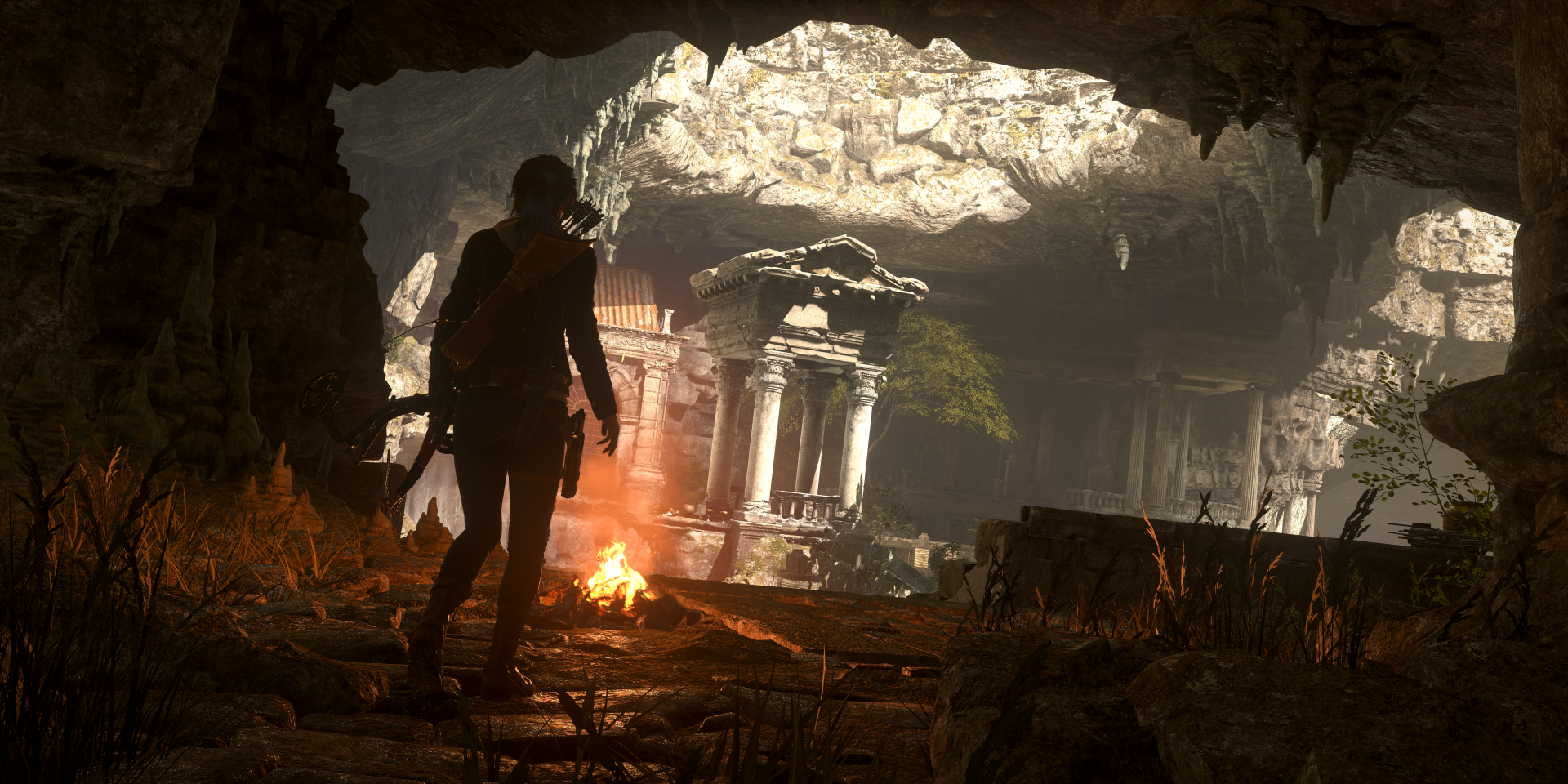 Silhouette of Lara Croft inside a dimly lit ancient cave, illuminated by a campfire, from the video game Rise of the Tomb Raider in 8K Ultra HD resolution.
