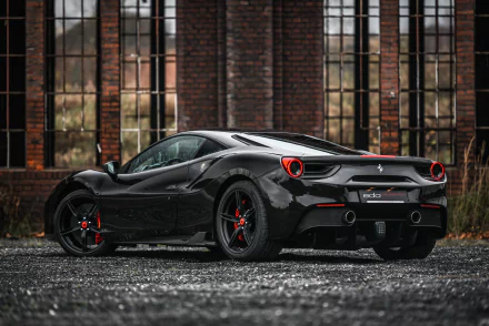 Black Ferrari 488 GTB by Edo Competition parked in front of a brick building, showcasing sleek tuning details in a 4K Ultra HD supercar wallpaper.