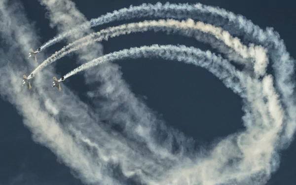 Military aircraft perform a synchronized aerial display at an air show, leaving intricate smoke trails against a clear sky, captured as an HD desktop wallpaper.