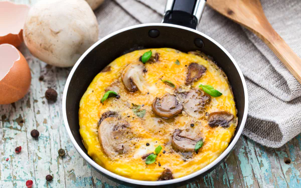 Close-up of a mushroom and egg omelette cooking in a pan, captured in vibrant 4K Ultra HD, set against a rustic wooden surface with kitchen utensils nearby.