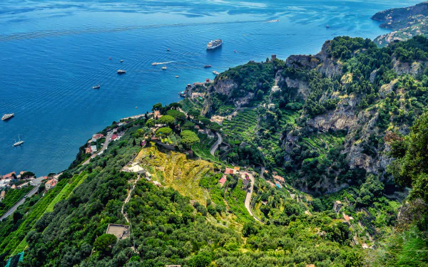 4K Ultra HD desktop wallpaper of the Amalfi Coast, Italy: cruise ship and boats on the blue sea bordered by terraced, man-made vineyards and rugged coastal mountains.