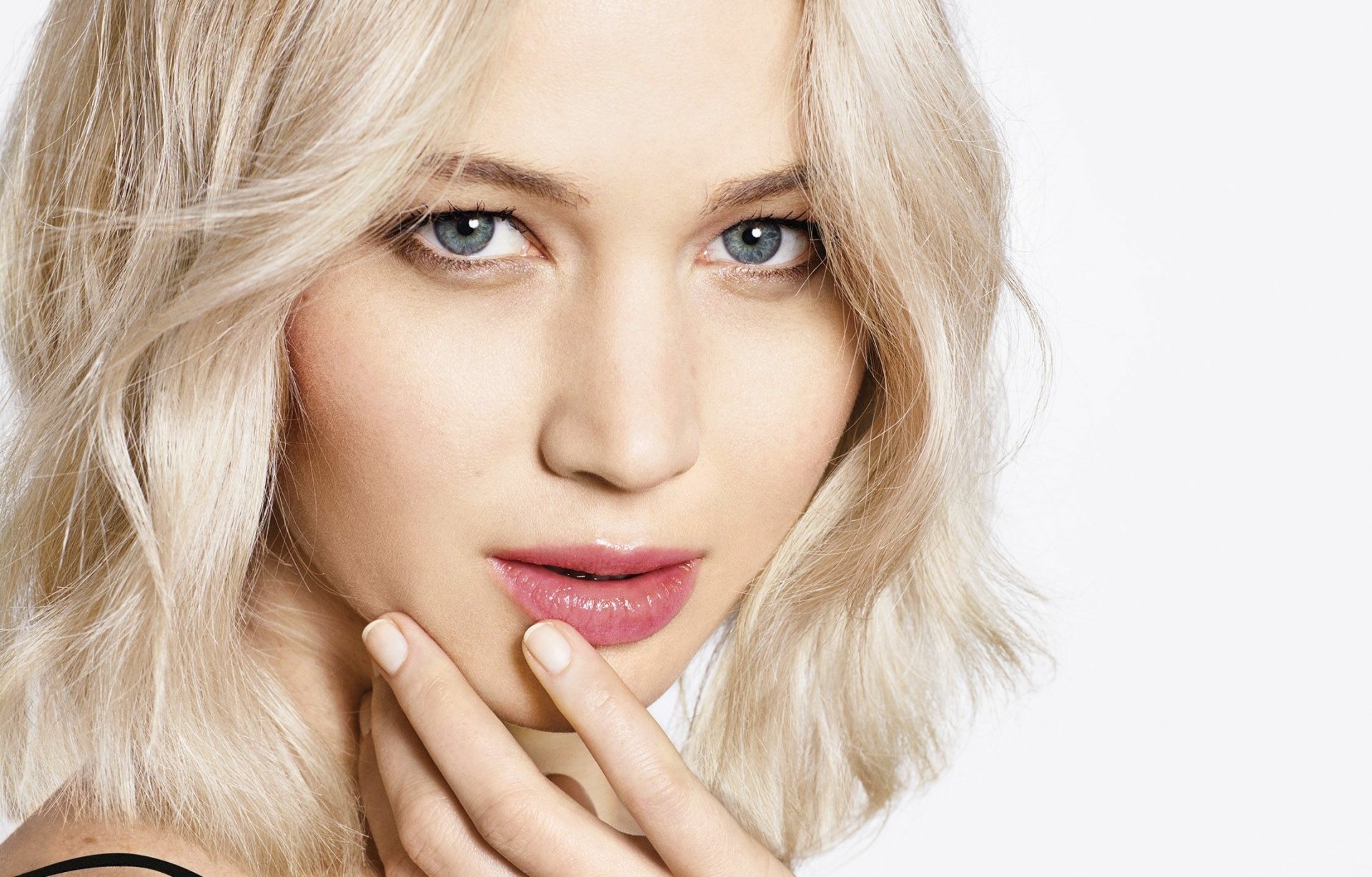 Close-up of an American actress with blonde hair and blue eyes, wearing subtle lipstick, showcasing her face with an elegant expression against a clean background.