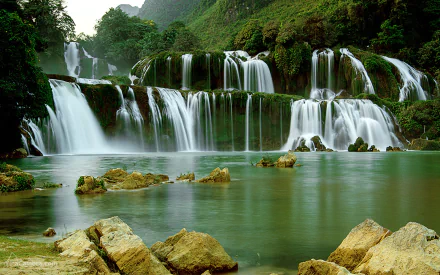 Ban Gioc-Detian Falls cascading through lush greenery on the China-Vietnam border, captured in a vibrant HD desktop wallpaper showcasing serene natural beauty.