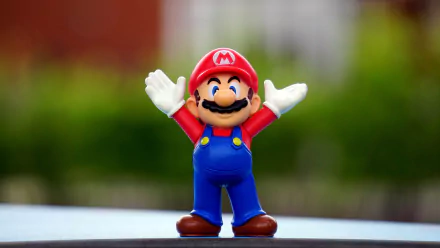 4K Ultra HD desktop wallpaper featuring a man-made Super Mario figurine with arms raised, set against a blurred natural background.
