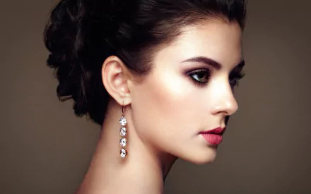 HD desktop wallpaper featuring a close-up profile of a brunette woman with elegant earrings and refined makeup against a neutral background.
