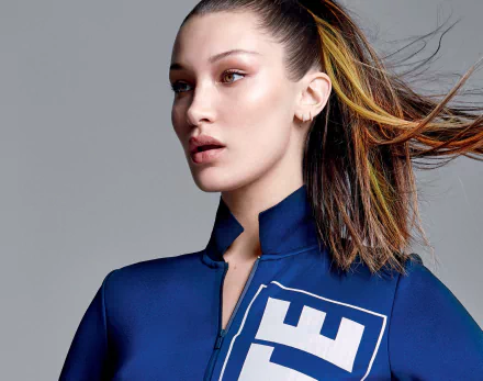 High-definition desktop wallpaper featuring American brunette model Bella Hadid with striking blue eyes, wearing a navy blue outfit against a gray background.