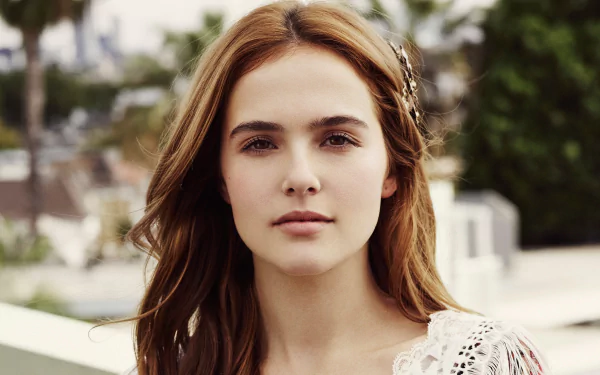 HD portrait of American actress Zoey Deutch with brown eyes and brunette hair, captured outdoors with a soft, natural background.