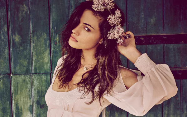HD desktop wallpaper of Australian actress Phoebe Tonkin with brunette hair, wearing a white blouse and a floral wreath against a rustic green wooden backdrop.