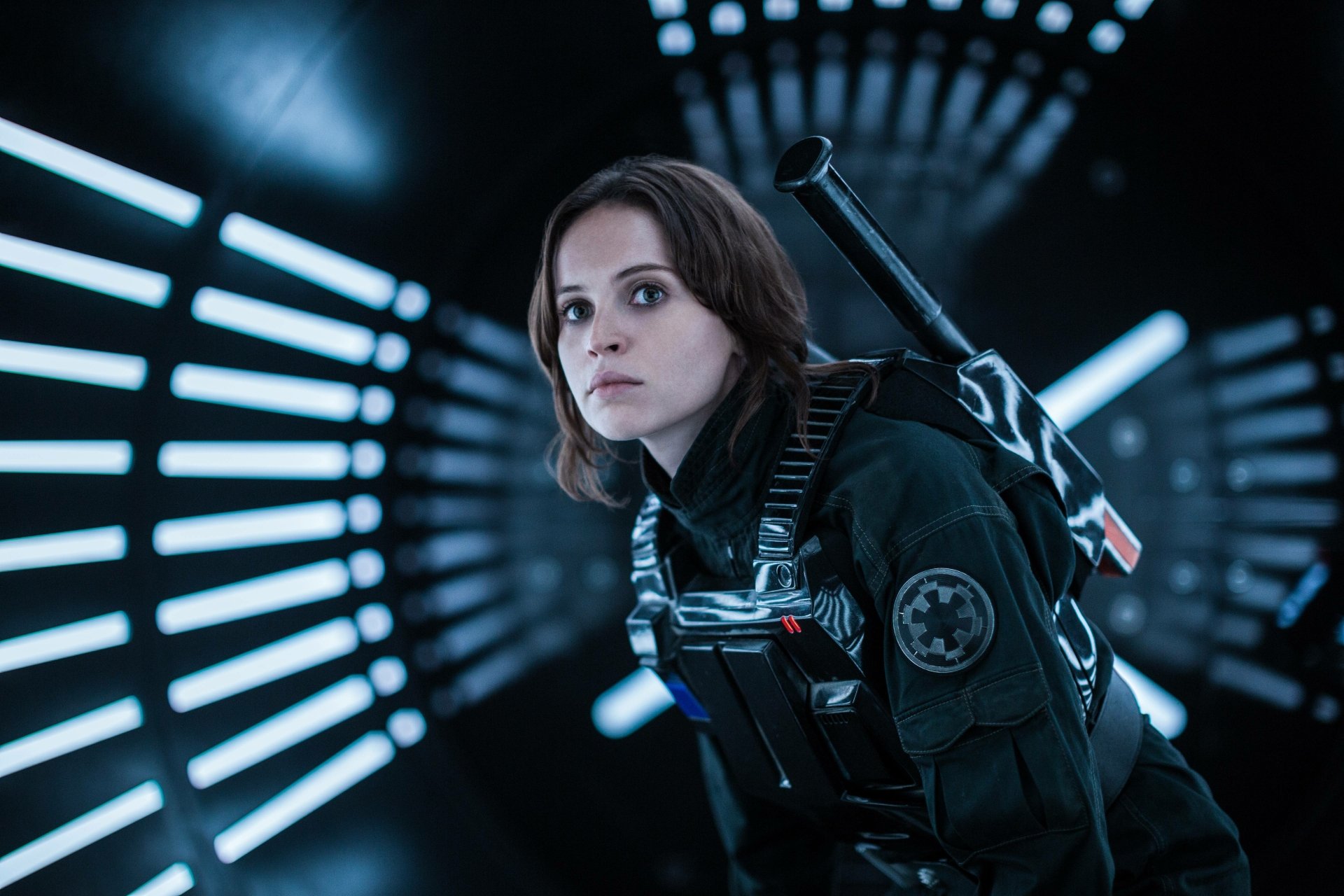 HD wallpaper featuring Jyn Erso (Felicity Jones) from Rogue One: A Star Wars Story, capturing her determined expression in a futuristic corridor with striking lighting.