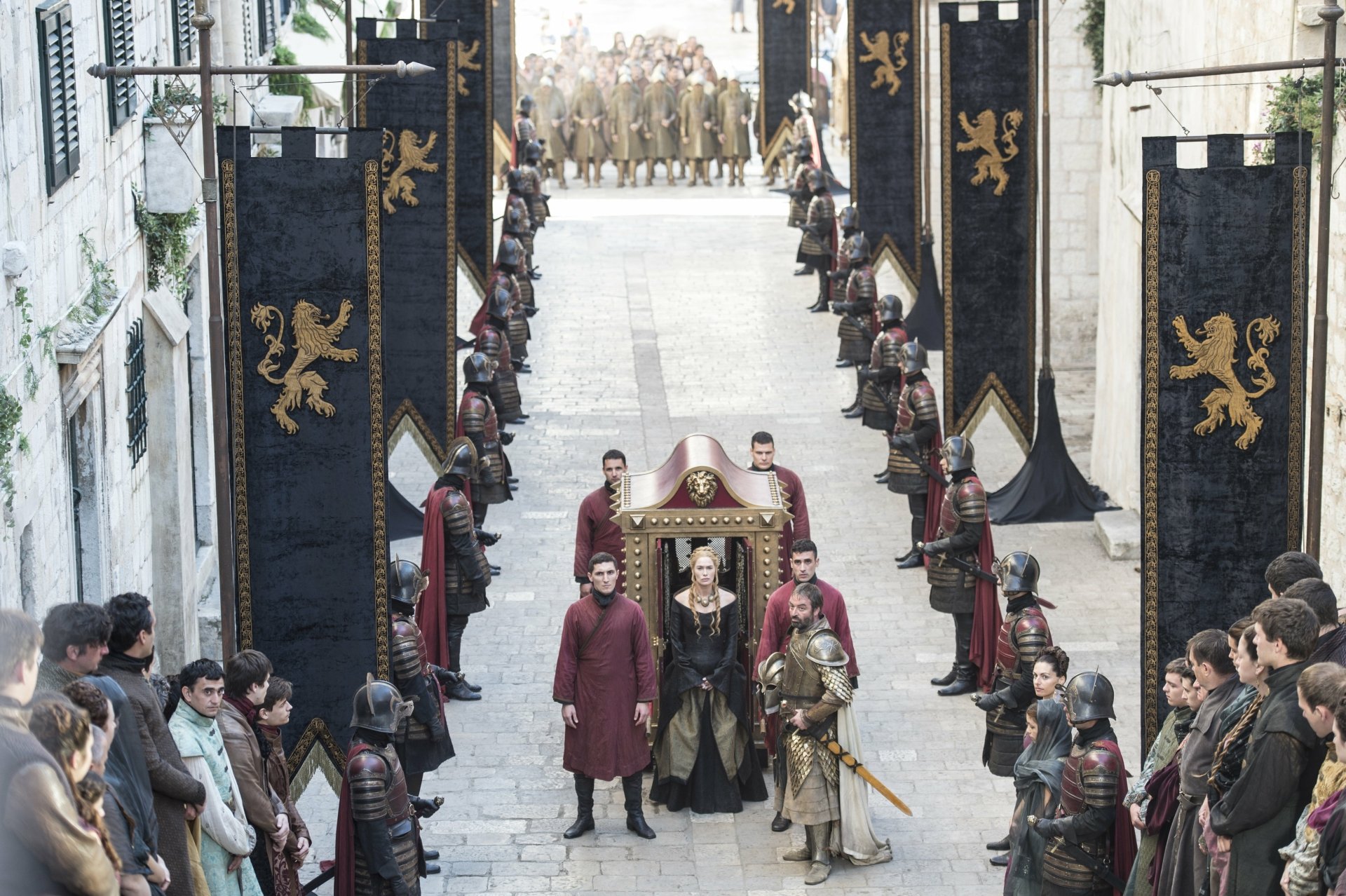 Lena Headey as Cersei Lannister leads a procession through a narrow street, flanked by soldiers and banners, in this dramatic scene from *Game of Thrones*, captured in stunning 4K Ultra HD.