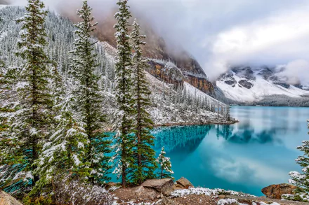 A stunning winter scene at Moraine Lake in Canada, featuring turquoise waters reflecting snow-capped mountains and evergreen trees, capturing the beauty of nature in HD detail.