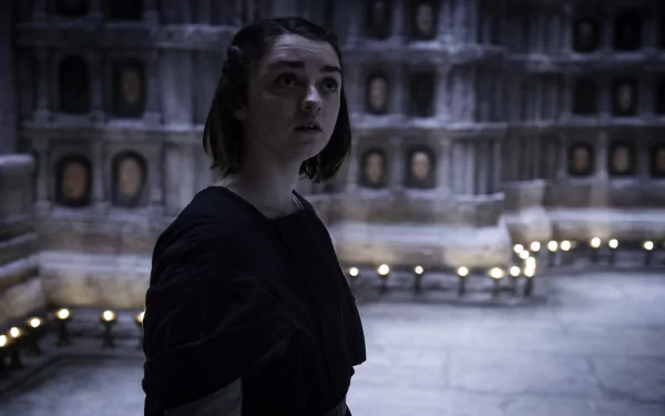 Maisie Williams as Arya Stark from Game of Thrones stands thoughtfully in a dimly lit chamber, captured in 4K Ultra HD for a PC desktop wallpaper.