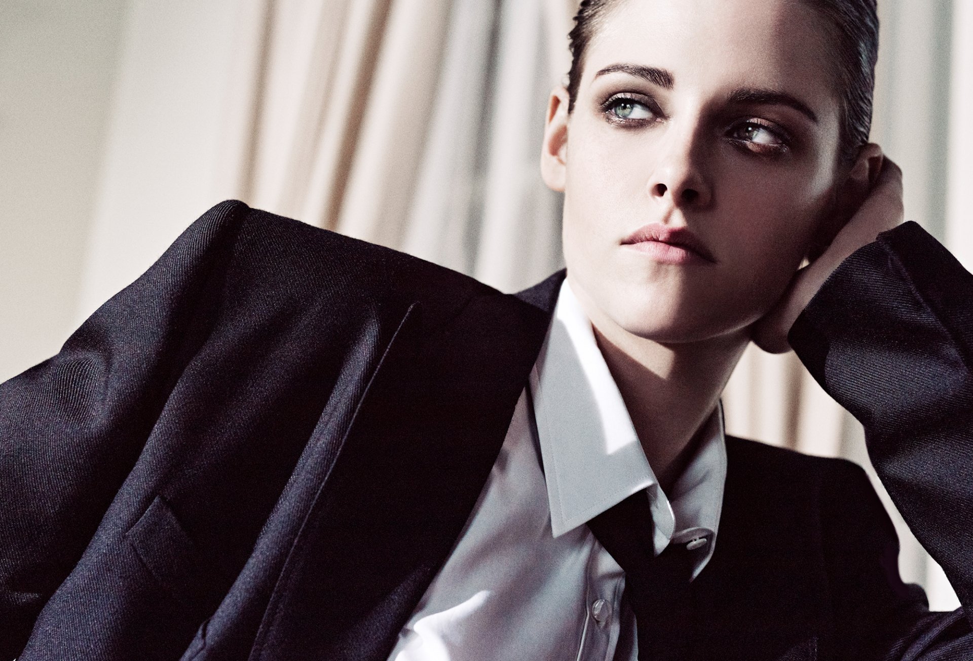HD desktop wallpaper of American actress Kristen Stewart in a suit, showcasing her striking green eyes and confident expression.