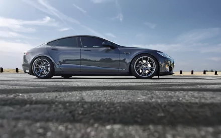 Silver Tesla Model S side profile on a coastal road under blue sky — 5K Ultra HD PC desktop wallpaper showcasing a Tesla Motors vehicle.